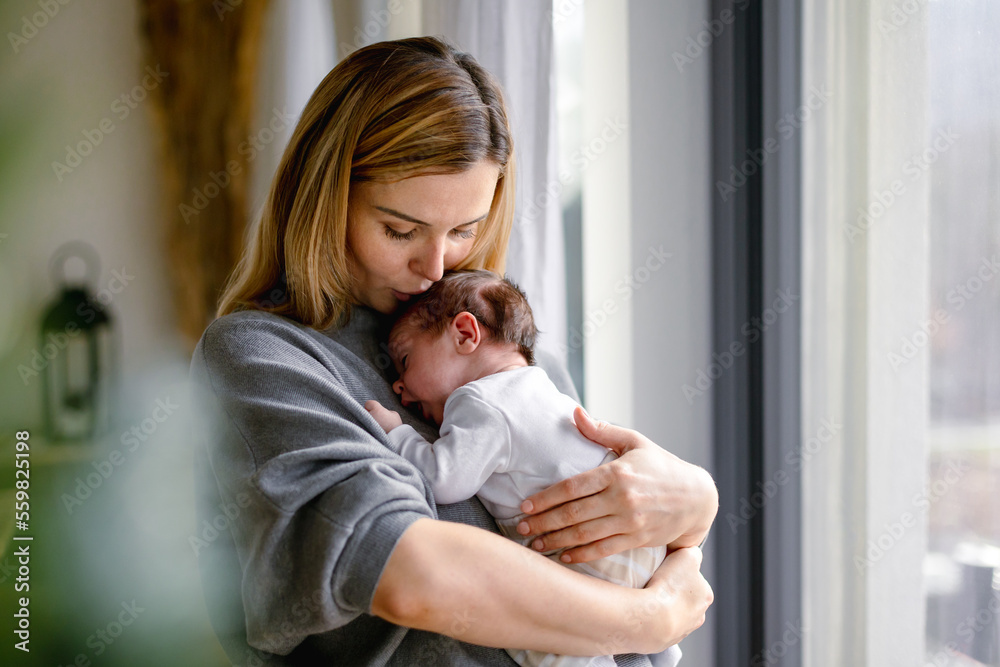 Loving mother hugs her little baby at home