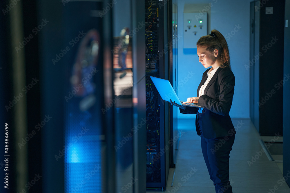 Female engineer working in server room at modern data center