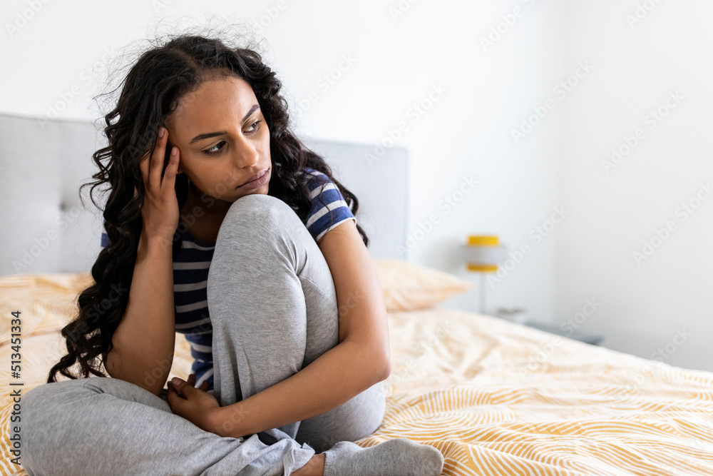 Worried woman sitting with head in hands at home